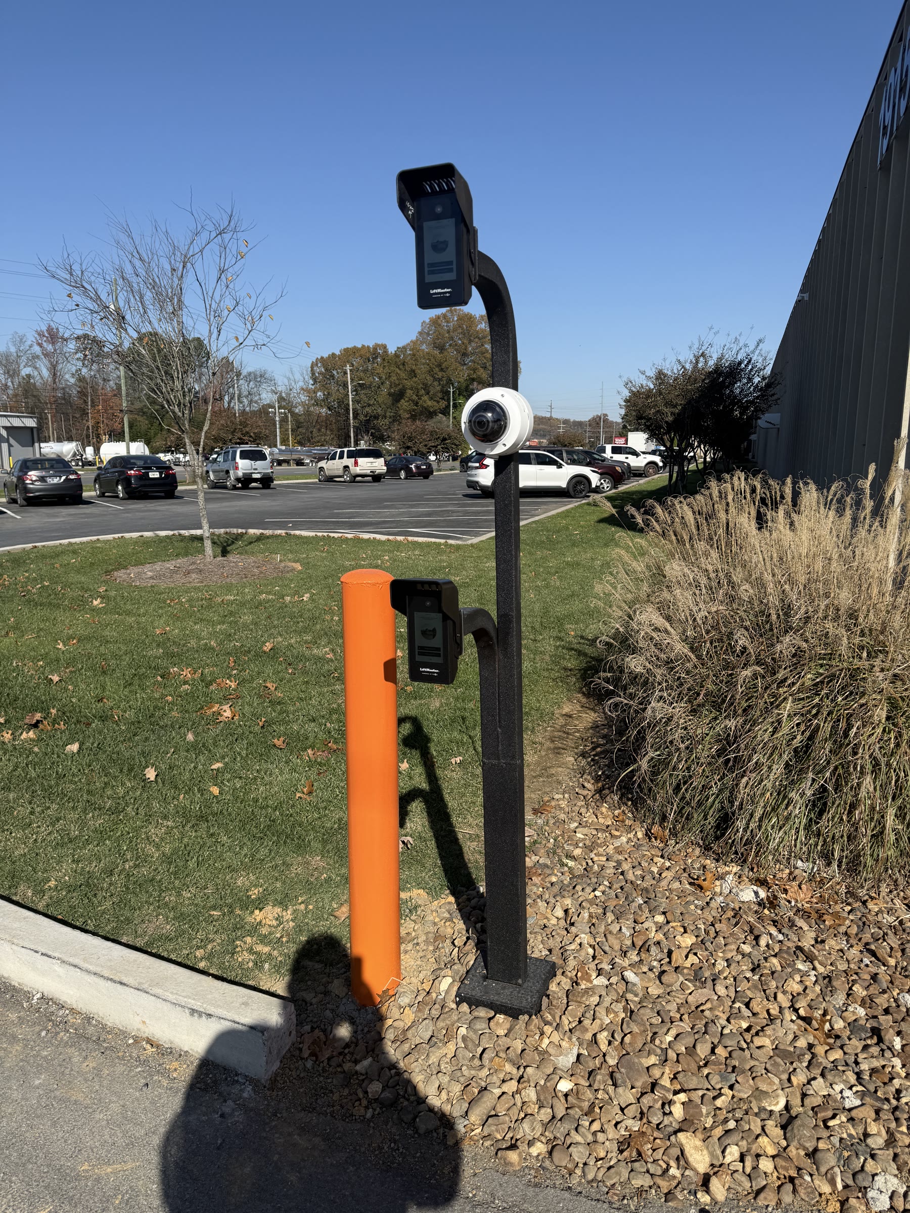 Dual-height LiftMaster video intercom and dome camera on a gooseneck pedestal at a commercial entry